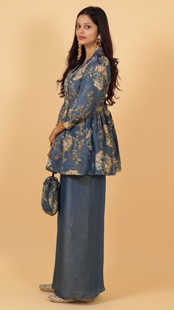 Woman wearing a blue floral blouse and dark pants against a beige background