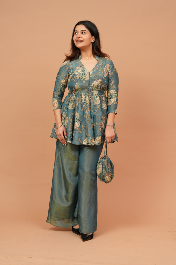 Woman wearing a floral top and wide-leg pants against a beige background