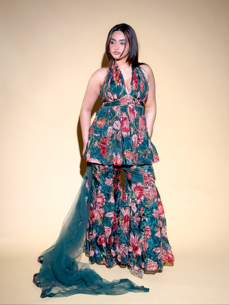 Woman wearing a floral dress with a long train on a plain background