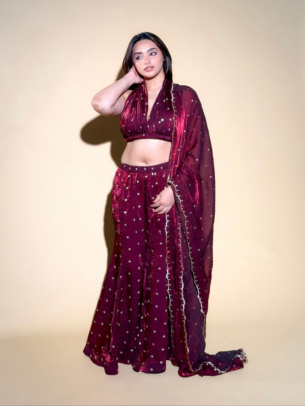 Woman wearing a maroon saree with a matching blouse against a beige background